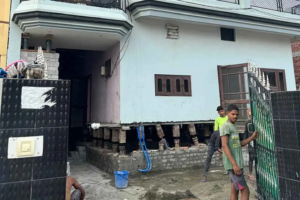 SRBL team member near a residential structure with visible balcony and building materials – representing expert house lifting and foundation repair services in Kolkata.