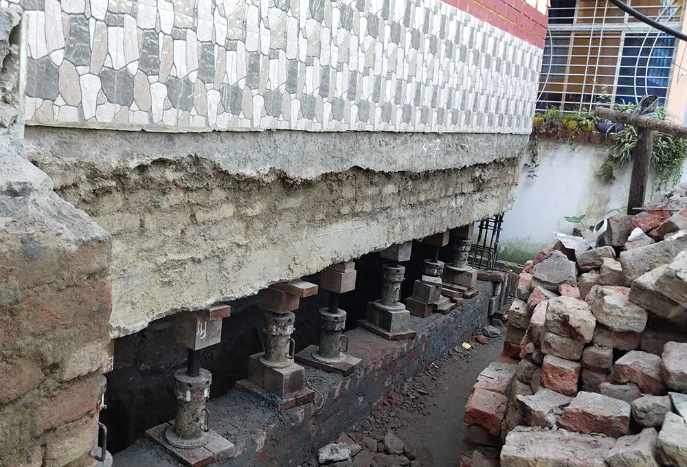 SRBL experts performing foundation repair with hydraulic jacks using brickwork, reinforced concrete, and mortar for precise structural stabilization